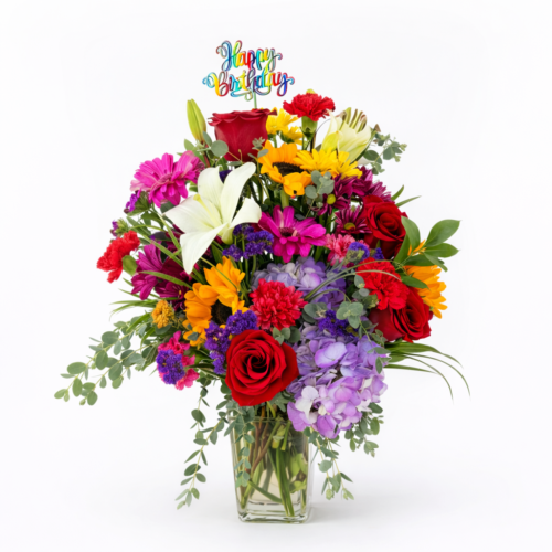 The Birthday Wishes arrangement from The Florist at Plantation includes red roses, white lilies, colorful blooms, lush greenery, and a “Happy Birthday” topper in a clear vase. Ideal for Clayton NC Flower Delivery.