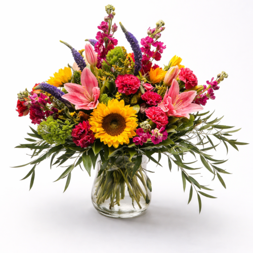 The Sunshine Celebration Vase features sunflowers, pink lilies, red carnations, purple veronica, and lush greenery in a clear glass vase—perfect for flower delivery in Clayton, NC.