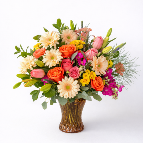 Lovely Gerberas is a vibrant floral arrangement in a brown vase, featuring pink tulips, orange roses, cream gerbera daisies, and yellow blooms. Expertly crafted by your local Clayton florist, it’s perfect for brightening any space.