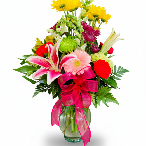 The Pretty Lily Vase features a clear glass vase filled with vibrant pink lilies and gerbera daisies, beautifully arranged by your Local Florist in Clayton and finished with a large pink ribbon bow.
