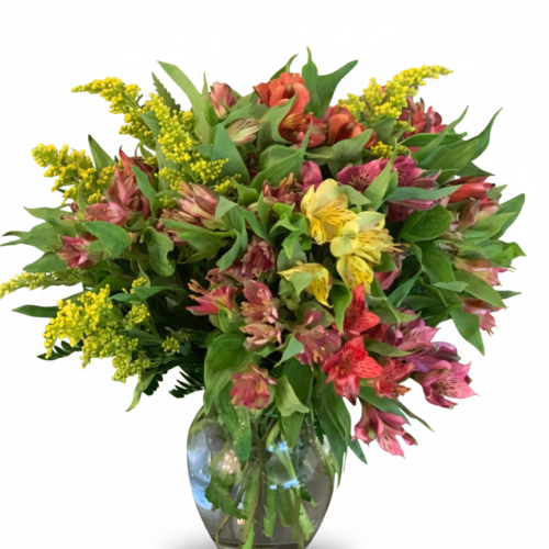 The Alstroemeria Sunset Bouquet from The Florist at Plantation features a vibrant mix of yellow, pink, red, and orange flowers with green leaves—beautifully arranged in a clear glass vase. Available for delivery in Clayton, NC. Set against a white background.