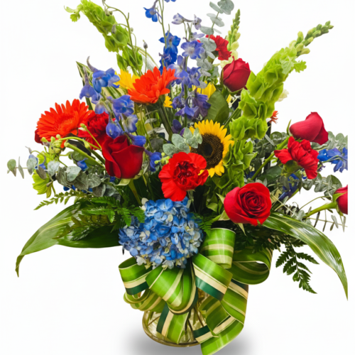 The Patriotic Honor Vase features red roses, orange gerbera daisies, sunflowers, and more in a glass vase. Perfect for any occasion with fast, reliable Flower Delivery in Clayton NC.