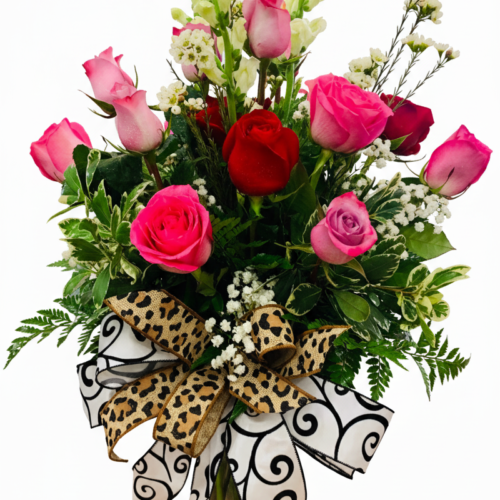 The Pinky Promise Bouquet features pink and red roses, white accent flowers, and greenery in a glass vase, finished with a large decorative bow of leopard print and black swirls from The Florist at Plantation.