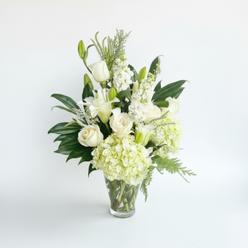 The White Lily & Rose Classic features an elegant mix of white roses, lilies, hydrangeas, and greenery in a clear glass vase—beautifully arranged by your local Clayton florist for a refined accent to any space.