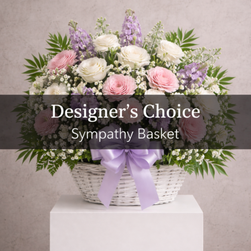 A white wicker basket with pink, white, and lavender flowers, greenery, and a lavender ribbon. Text overlay: "Sympathy Basket - Designer Choice." Clayton NC Flower Delivery by The Florist at Plantation.